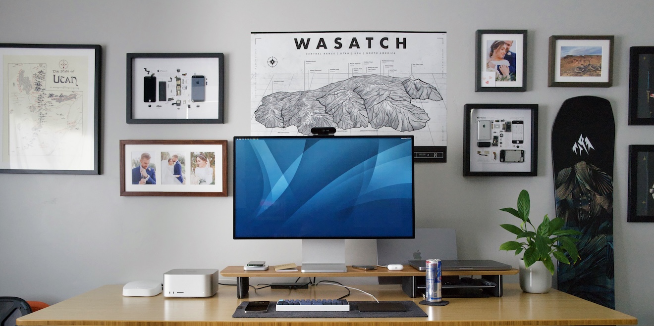 a photograph of my desk wall, showing my desk with various computer items on it, and a wall with a snowboard and various framed pieces of artwork displayed